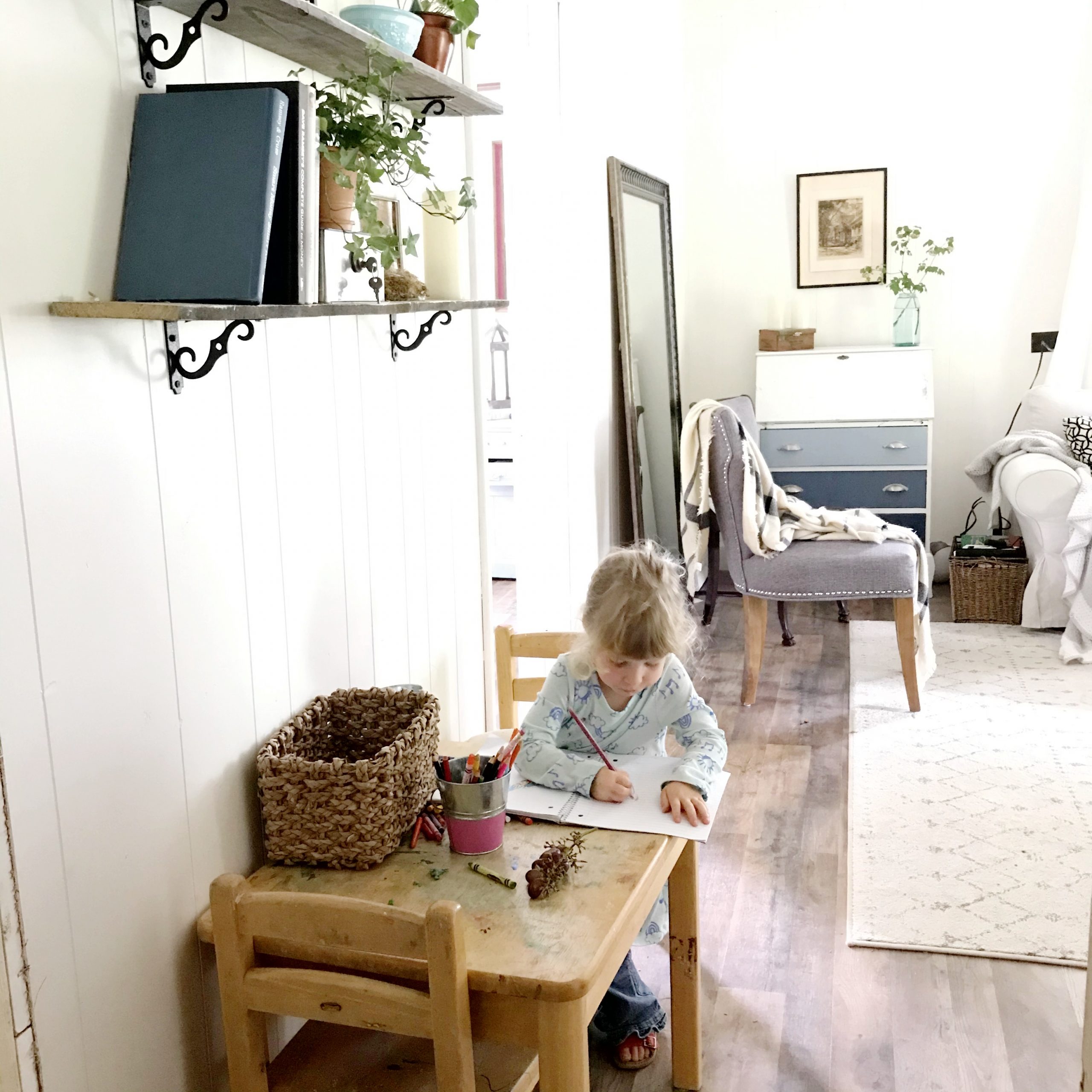 A preschooler sits and draws at a child-sized table.