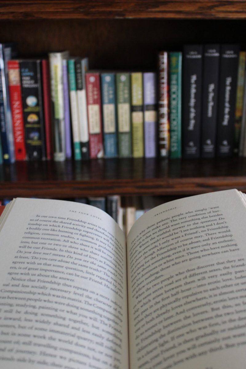 A book lays open in front of a bookshelf.