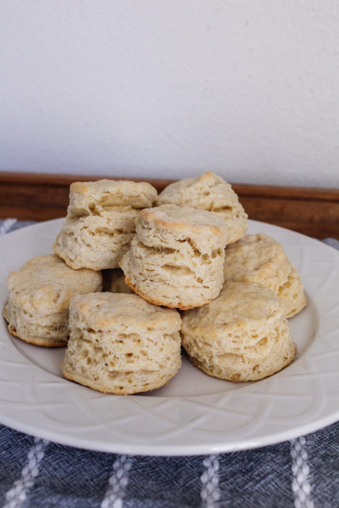 A pile of freshly-baked scones sits on a white plate.