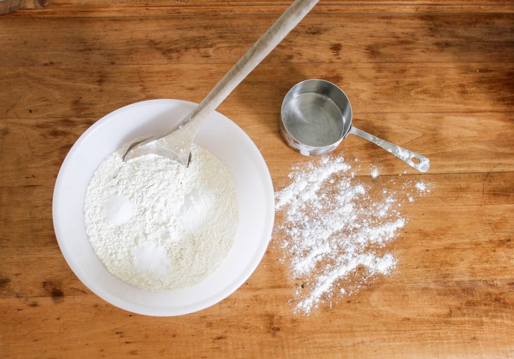Flour and other dry ingredients rest in a white bowl, waiting to be stirred together.