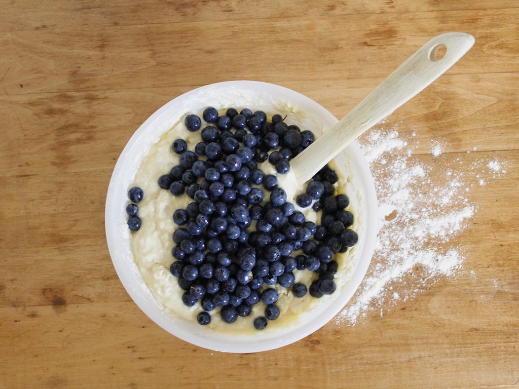 A bunch of blueberries has been dumped into a bowl and is waiting to be stirred into the batter.
