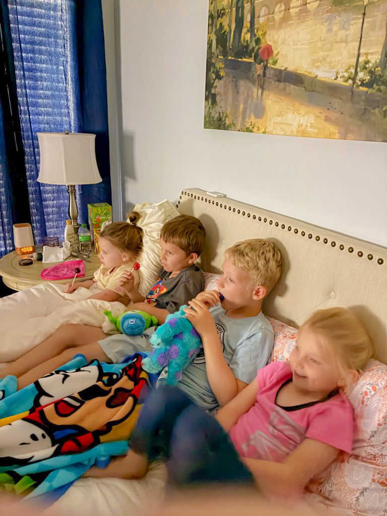 Children snuggled up with treats watch a movie together.