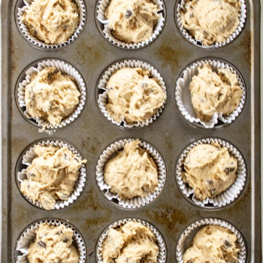 A muffin pan is filled with batter, waiting to be baked.