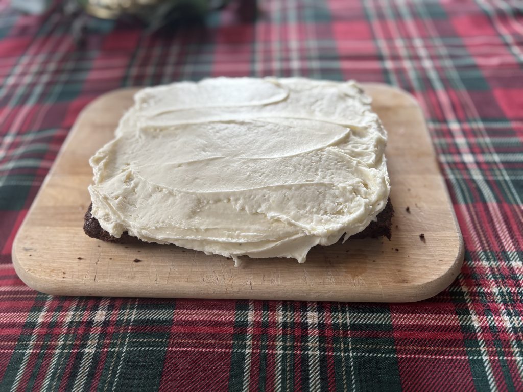 Peppermint cream cheese frosting is spread over a batch of brownies.